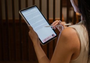 Professional woman analyzing a document on a digital tablet in a modern office setting.